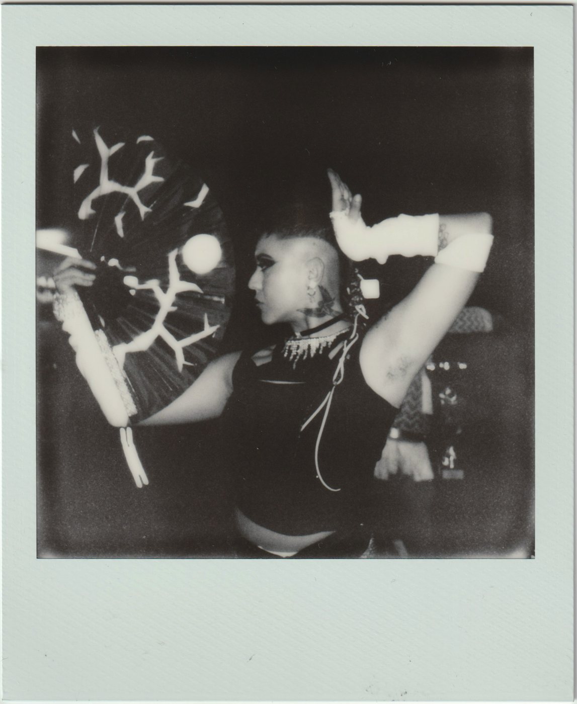 Profile of a person raising an arm beside a large patterned fan